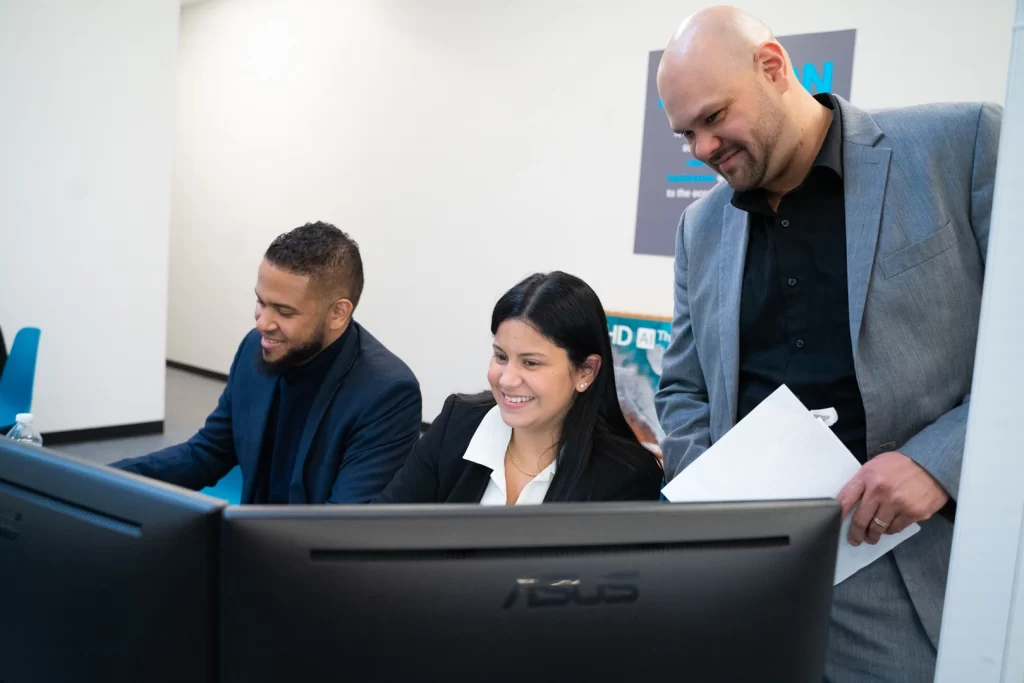 A picture of JBS employees filing taxes for clients on computers while smiling